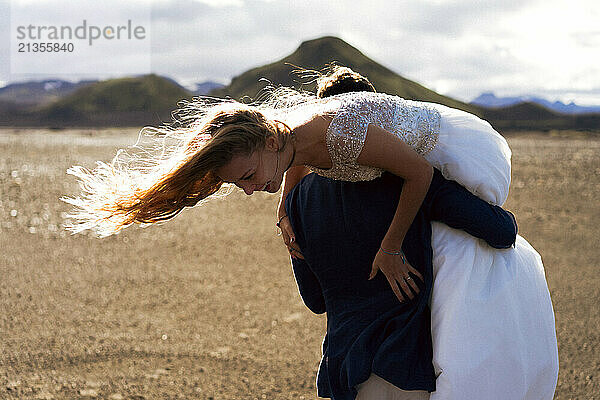 The groom carries the bride on his shoulder