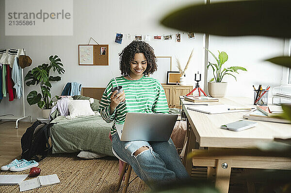 Smiling girl using laptop near desk at home