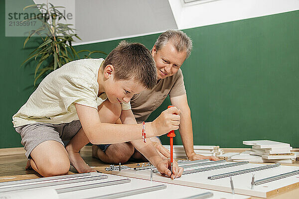 Son and father assembling new furniture together at home