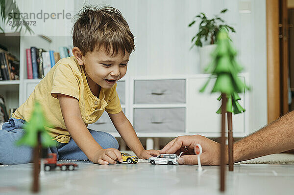 Boy and father playing with toy car at home