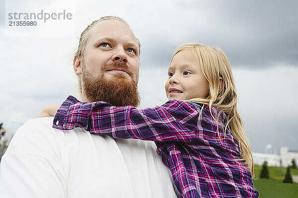 Father with daughter under overcast sky