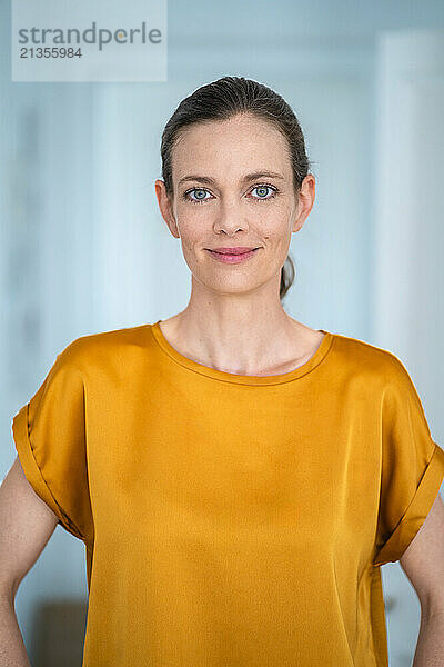 Smiling mature woman wearing yellow t-shirt at home