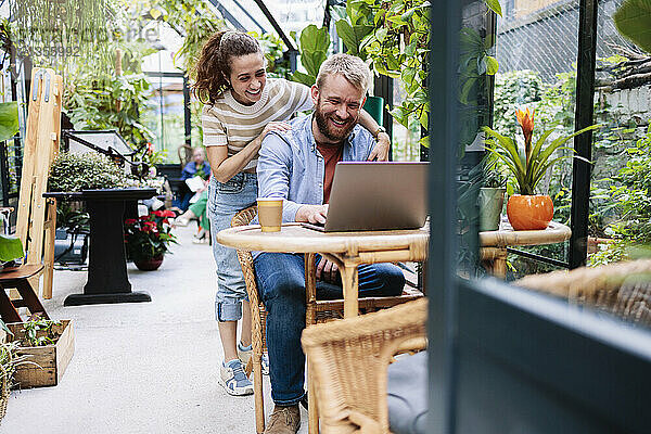 Happy couple working on laptop in greenhouse