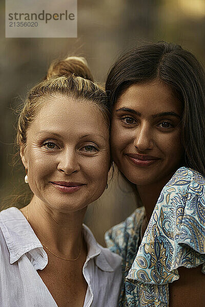 Smiling teenage daughter cheek to cheek with mother