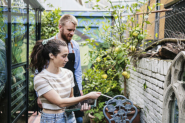 Couple examining built structure of greenhouse