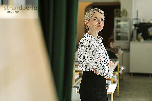 Smiling businesswoman with arms crossed standing in bookstore