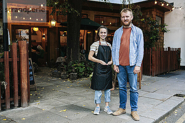 Cafe owners standing on paving stone outside coffee shop