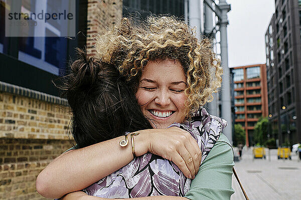 Happy lesbian couple hugging each other in city