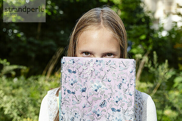 Blond girl hiding behind book