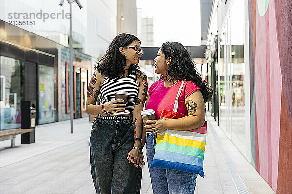 Young gay couple holding hands and walking at street