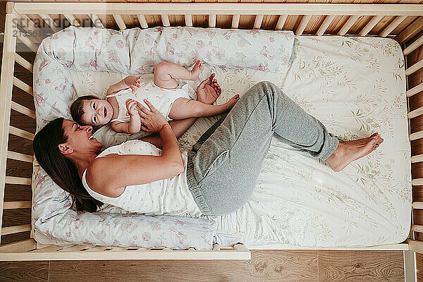 Happy mother lying down with daughter on bed at home