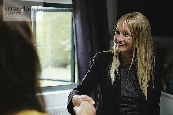 Smiling businesswoman shaking hand with client at home office