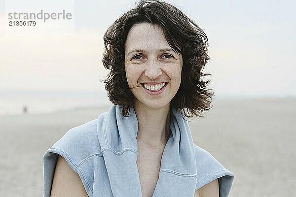 Happy woman with sweater at beach