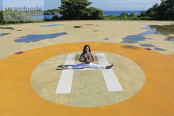 Yoga instructor doing split at public park on sunny day