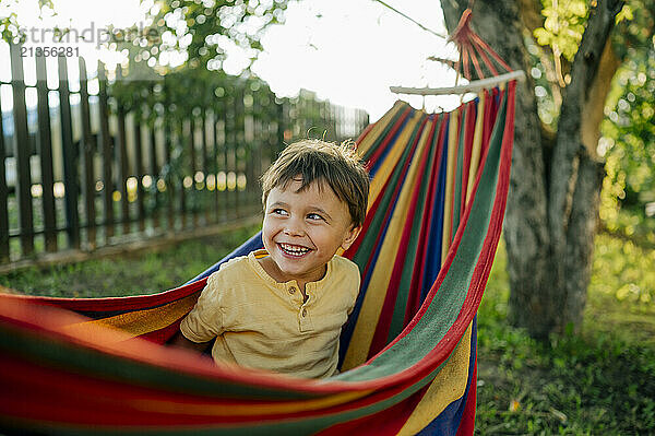 Cute boy laughing enjoying summer in colorful hammock