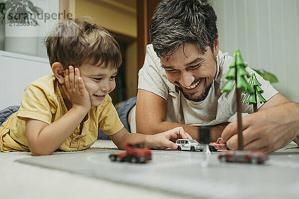 Happy father and son playing with toy cars at home