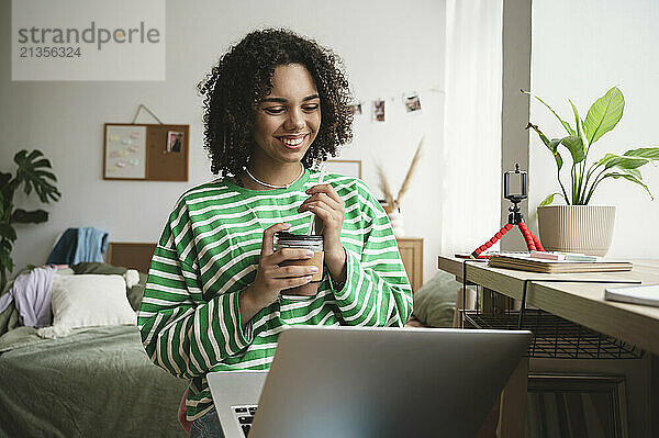 Happy girl using laptop in bedroom at home