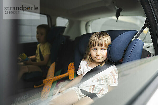 Siblings in car seats with fastened seat belt