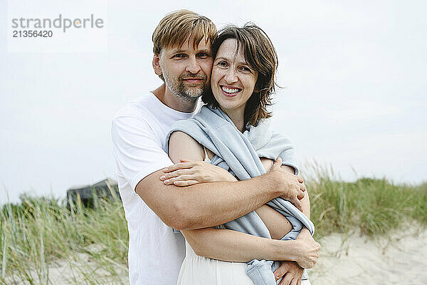 Mature man embracing girlfriend at beach