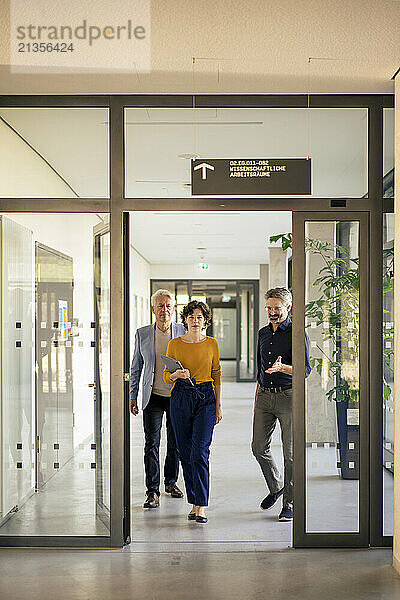 Businesswoman walking with colleagues in office doorway