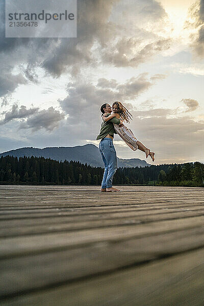 Mature woman carrying daughter and playing on jetty