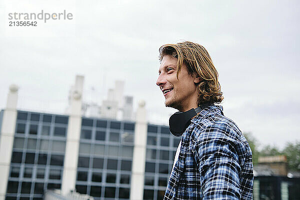 Smiling young man with long hair wearing plaid shirt