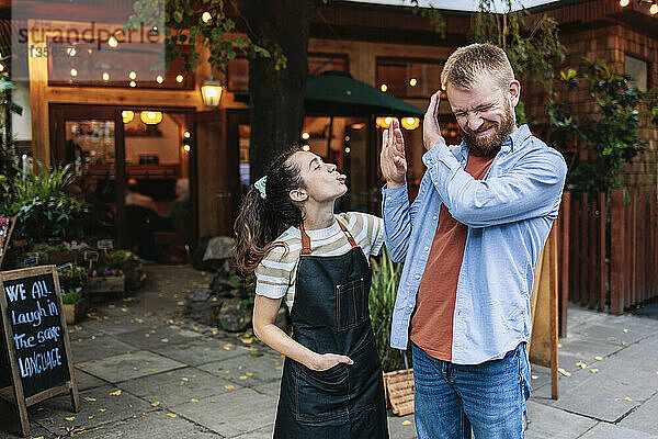 Mischievous couple spending leisure time with each other outside cafe