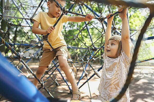 Siblings climbing on rope jungle gym