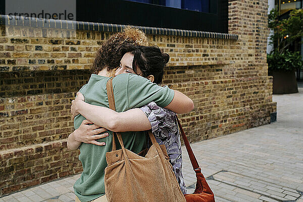 Happy lesbian couple hugging each other near building