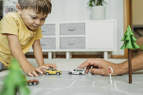 Focused boy and father playing with toy car at home