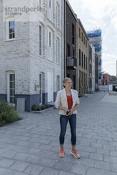 Contemplative woman standing on paving stone near building