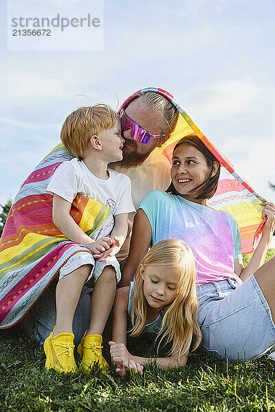 Family under blanket on sunny day at park