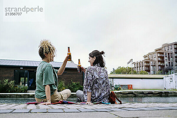 Happy lesbian couple having beer under sky