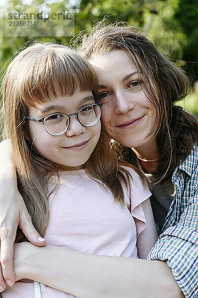 Smiling mother embracing daughter wearing eyeglasses