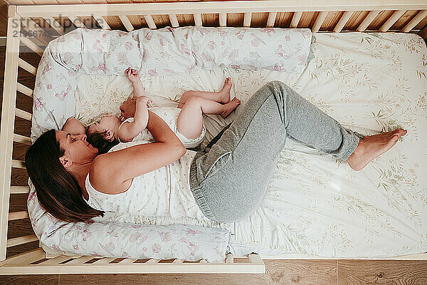 Mother sleeping with daughter on bed at home