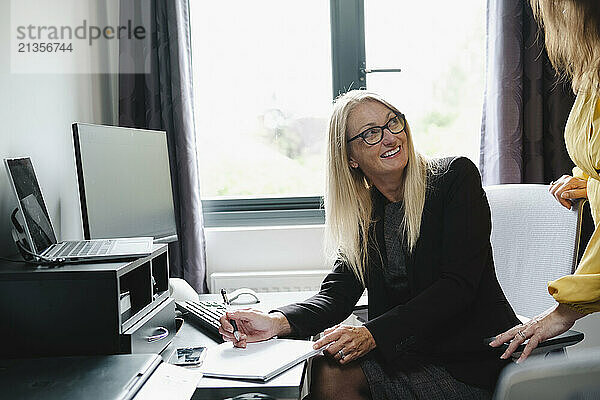 Smiling businesswoman looking at colleague and working at home office