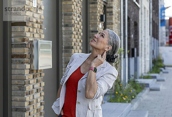 Gray haired woman wearing jacket spending leisure time near building