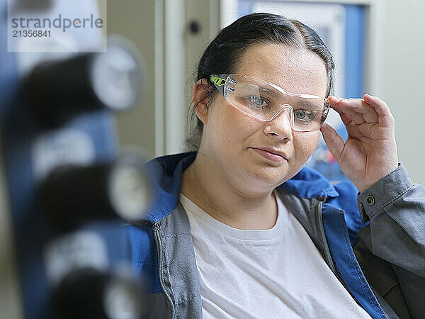 Trainee holding protective eyeglasses at workshop