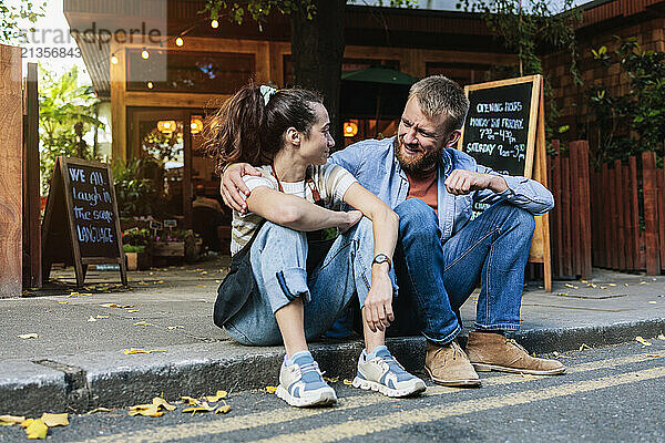 Cafe owners spending leisure time sitting outside coffee shop