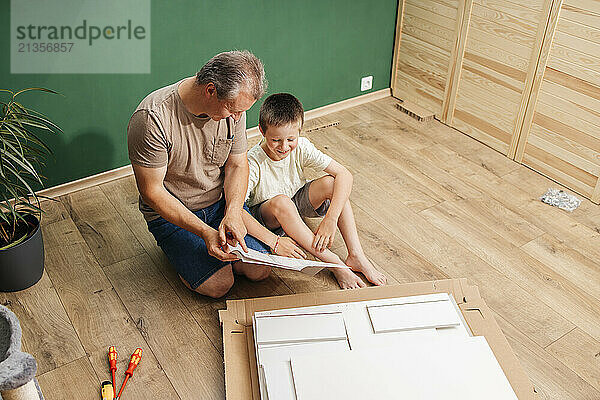 Father explaining instruction manual to son at home