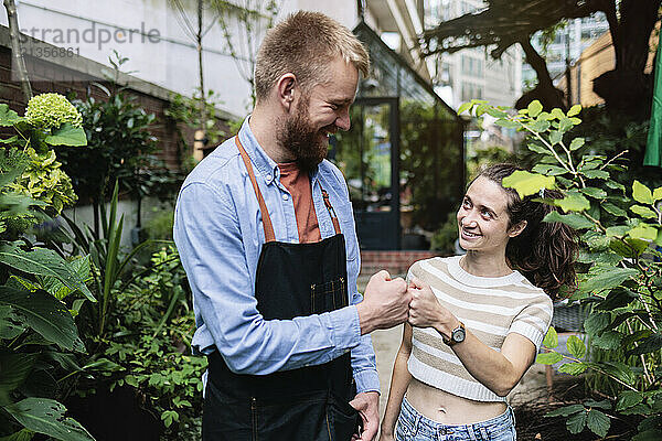 Happy couple doing fist bump at garden centre