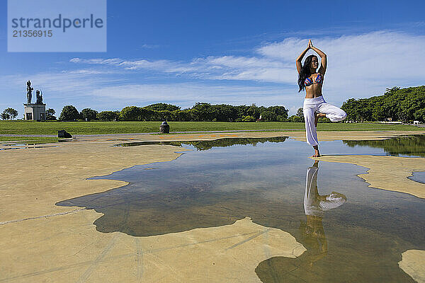 Yoga teacher doing tree pose in Bali at public park