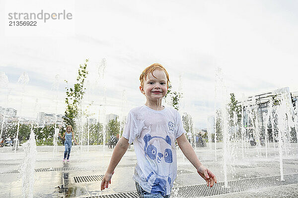 Happy boy playing near fountain in park