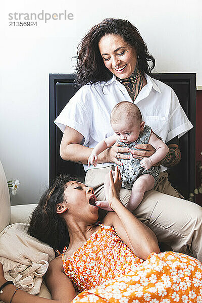 Playful girl with mother and baby at home