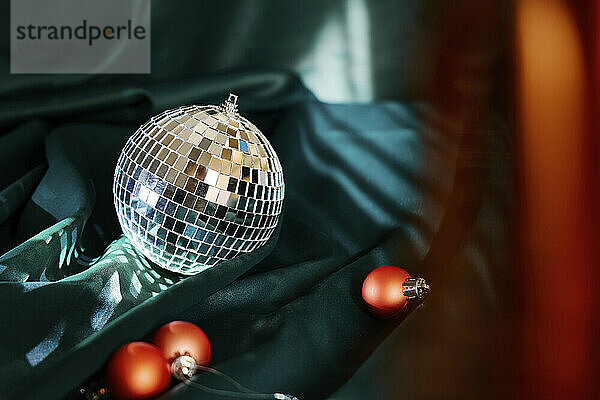 Silver colored disco ball and baubles on green cloth