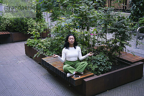 Carefree woman with eyes closed practicing yoga at park