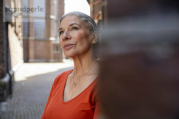 Contemplative beautiful senior woman in red casual