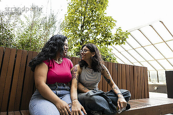 Happy lesbian couple sitting on bench at park