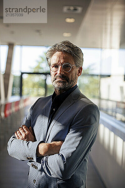 Businessman standing with arms crossed in office