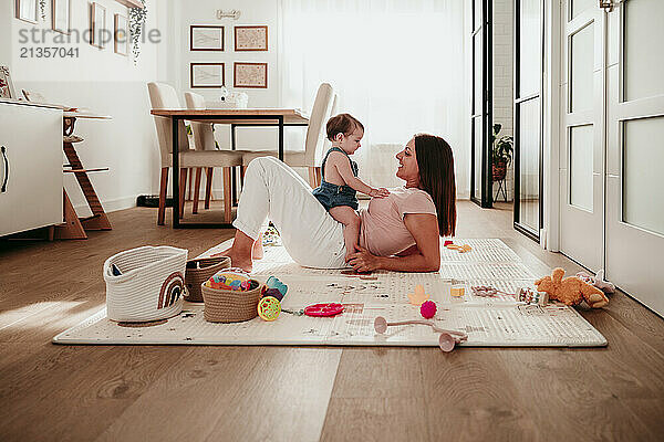 Baby girl sitting on mother and playing at home